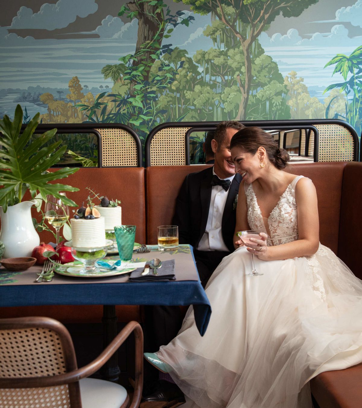 Bride and groom celebrating in a leather booth beneath the mural at St. Neo's Brasserie, Savannah wedding venue