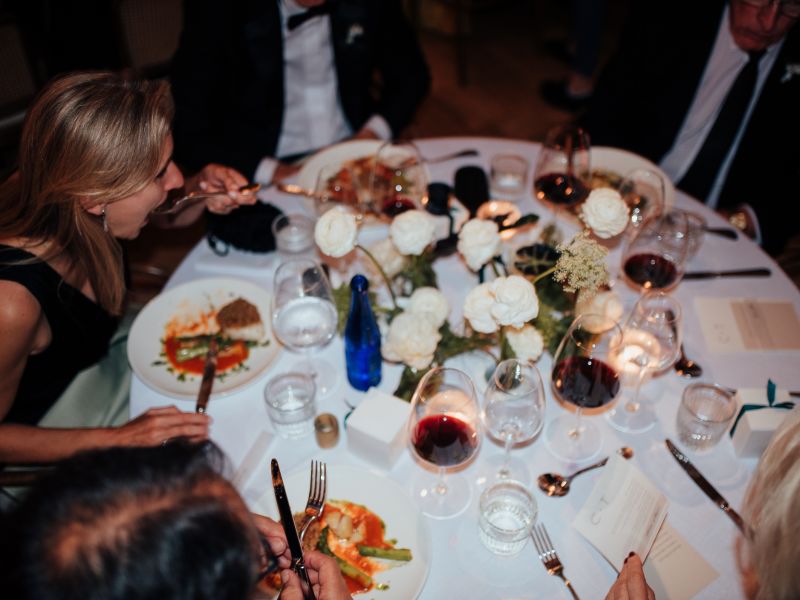 Guests dining around a candlelit table with white roses and wine at St. Neo's Brasserie