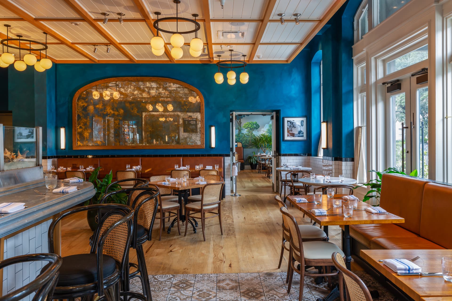 St. Neo's Brasserie dining room with blue walls, globe pendant lights, and leather banquettes