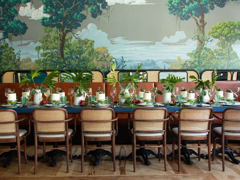 Banquet table set beneath a painted landscape mural