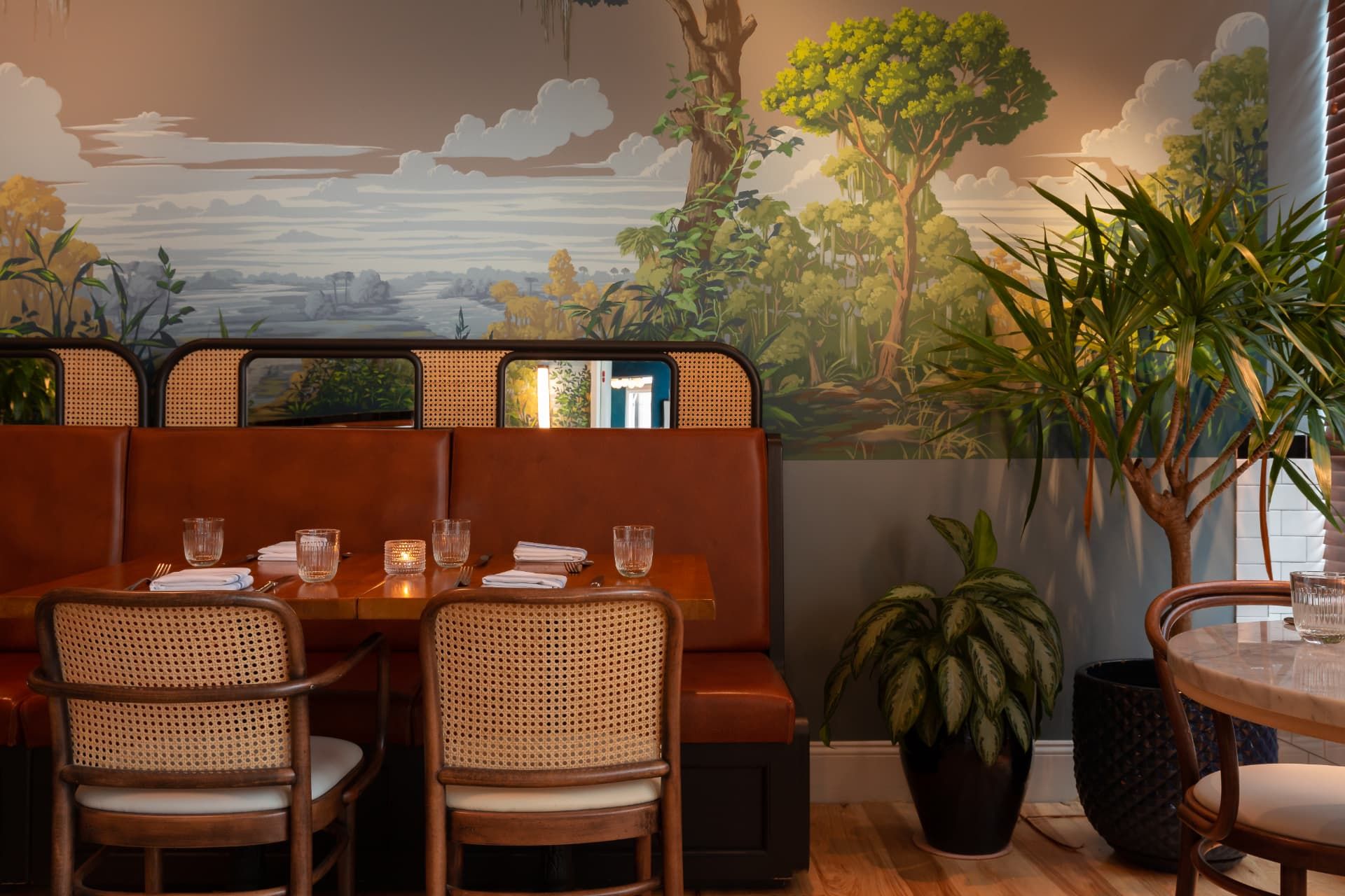 Leather banquette seating beneath a hand-painted Lowcountry mural at St. Neo's Brasserie